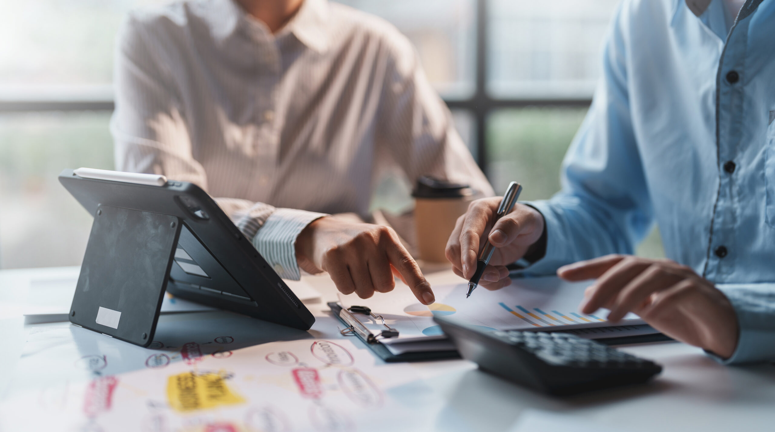 Businesspeople consulting on investment project work and marketing strategy planning and using a calculator and documentation. Mah Financial Services